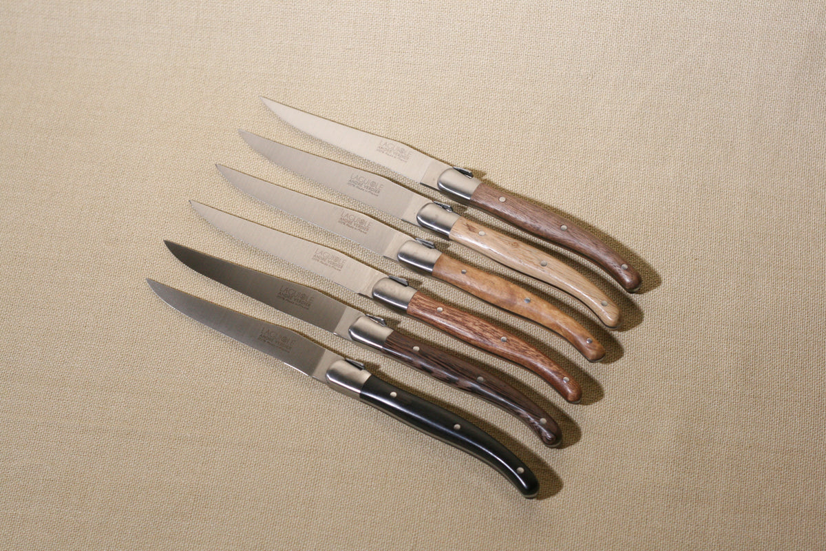 Laguiole Deluxe with mixed wood handles on a neutral background