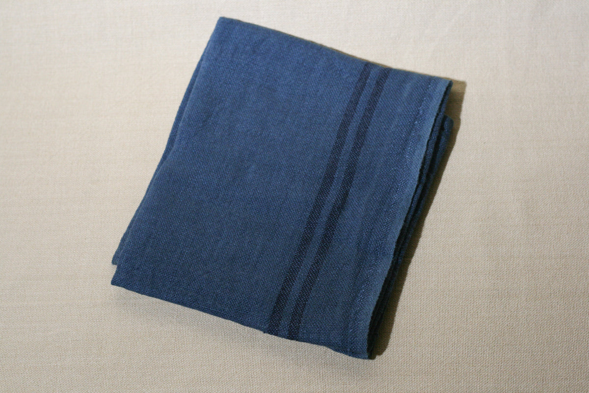 Striped linen dish towel in carbon on a neutral background.