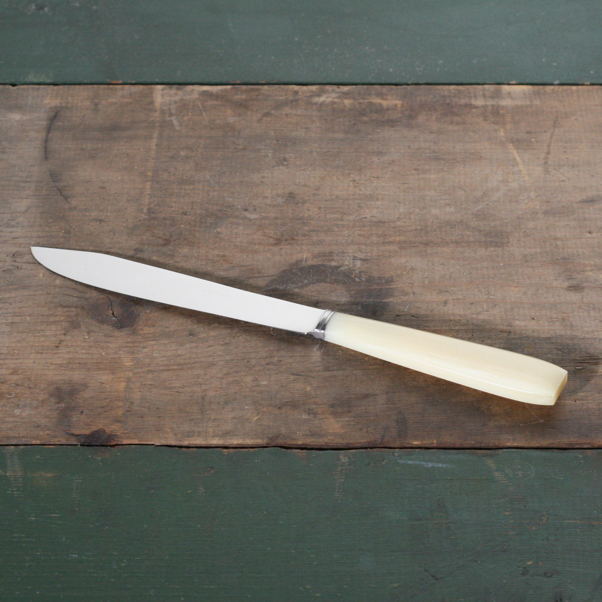 White handled vintage table knife on a wooden table.
